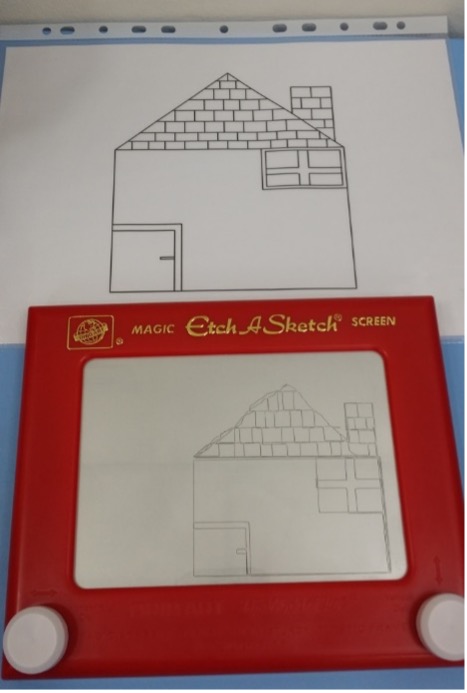 Etch-a-Sketch displaying a partially copied house beside the detailed house template.