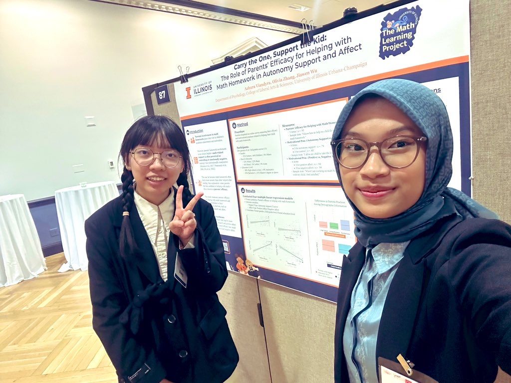 Olivia and Azhura standing beside their research poster about parental support during children's mathematics homework.